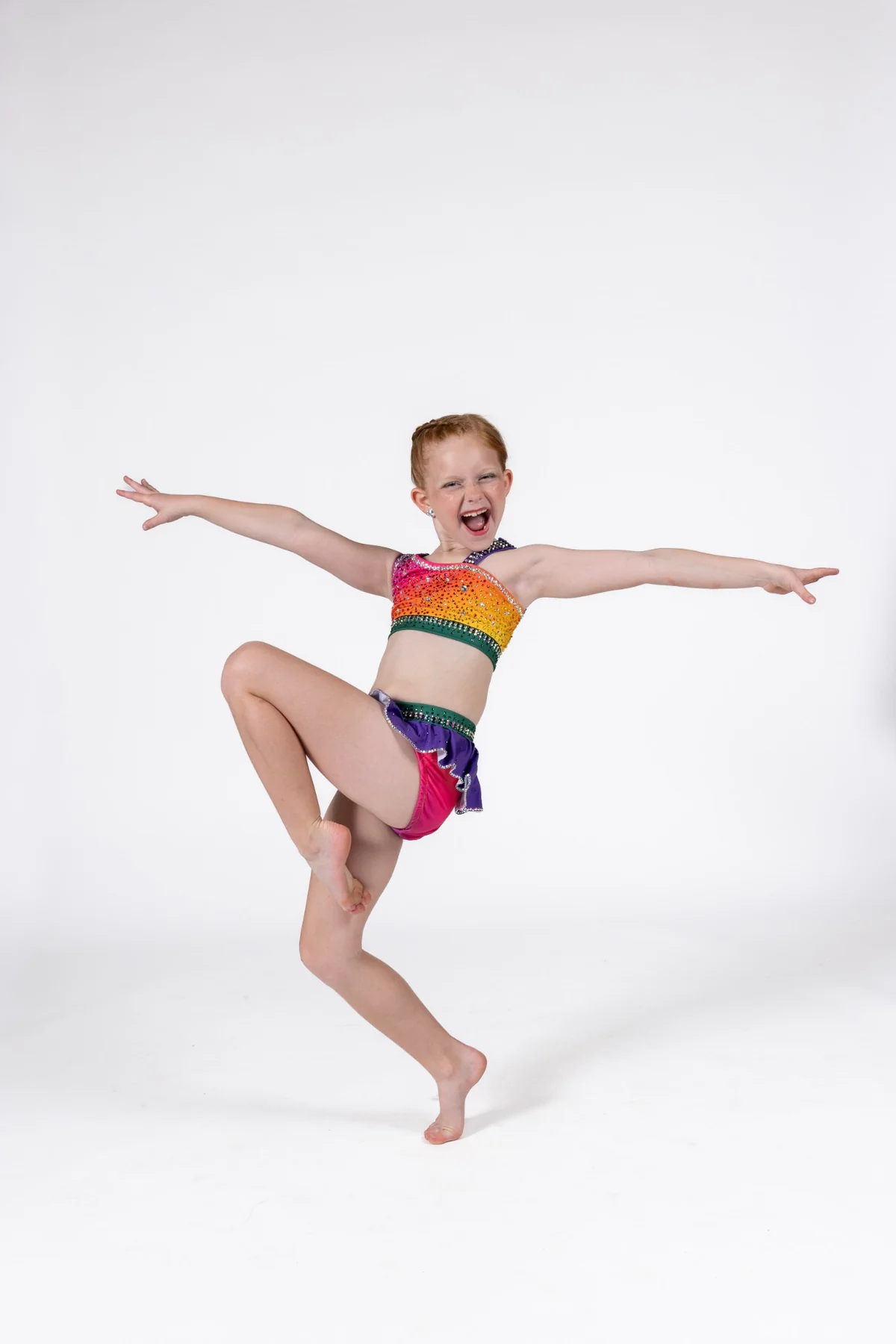 Young dancer celebrating movement in a bright rainbow costume
